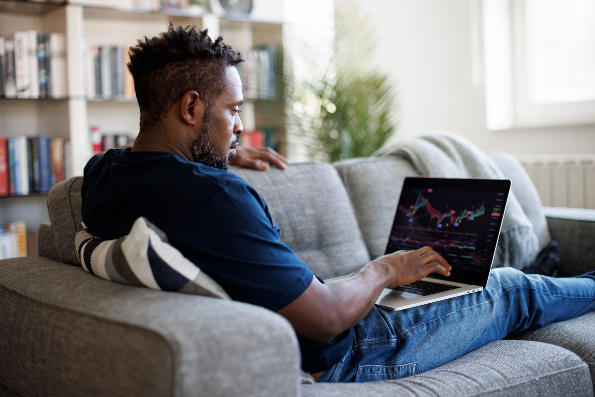 Man analyzing stock market with charts on laptop computer screen at home